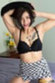 Arms raised removing her top wearing black bra