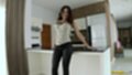 Leaning against counter wearing jeans