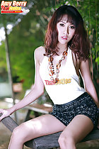 Seated on rocking horse long hair over her shoulders wearing necklace in tshirt wearing short skirt