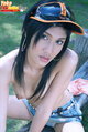 Seated topless tendrils of long hair falling over her small breasts wearing sun visor